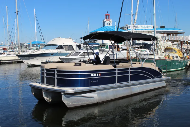 Slide: The Image of 2025 Harris Cruiser 230 pontoon boat docked in a marina with other boats. - 4