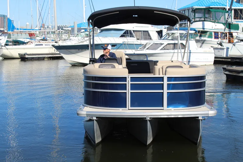 Slide: The Image of 2025 Harris Cruiser 230 pontoon boat docked in a marina, featuring a sleek blue design. - 6