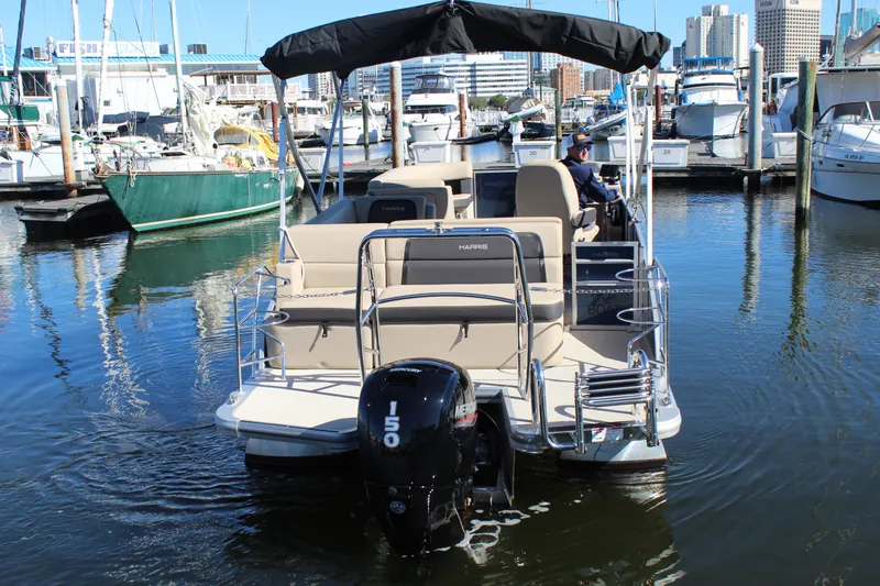 Slide: The Image of 2025 Harris Cruiser 230 pontoon boat docked in a marina, featuring a Mercury 150 engine. - 9