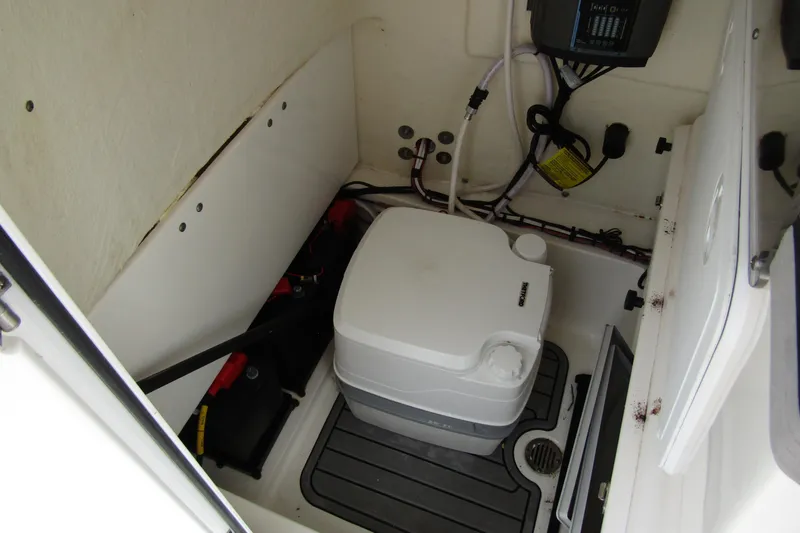 Slide: The Image of 2021 Tidewater 2700 Carolina Bay boat interior with portable toilet and storage compartment. - 19