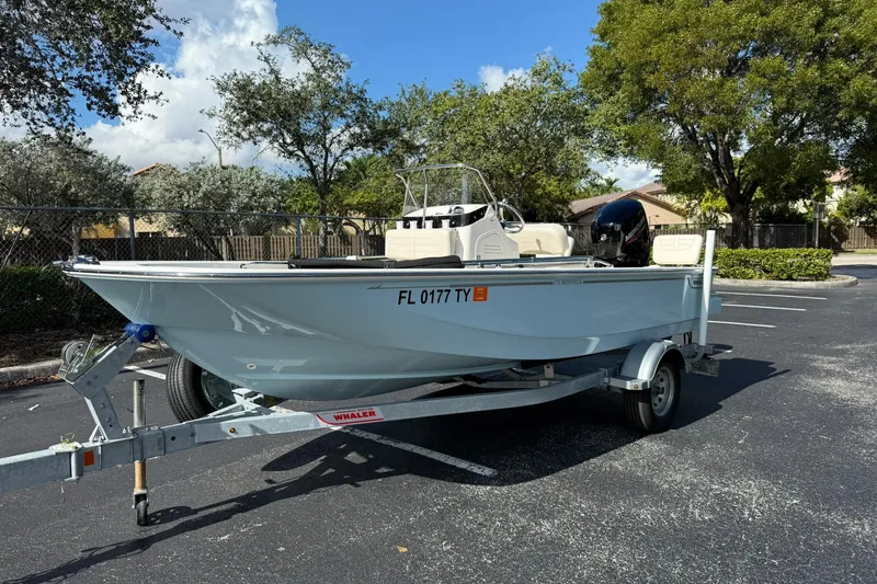 Slide: The Image of 2025 Boston Whaler 170 Montauk boat on trailer in parking lot, sunny day. - 1