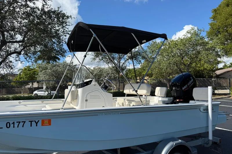 Slide: The Image of 2025 Boston Whaler 170 Montauk boat with canopy and Mercury engine in a parking lot. - 10
