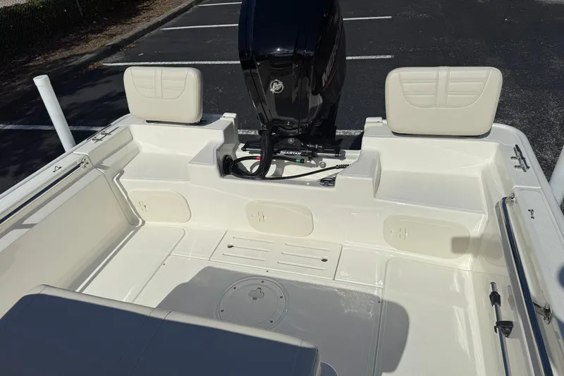 Slide: The Image of 2025 Boston Whaler 170 Montauk boat interior with seating and motor in a parking lot. - 21
