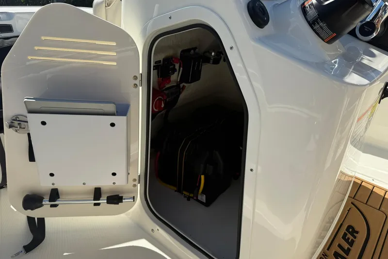 Slide: The Image of 2025 Boston Whaler 170 Montauk storage compartment with open door and visible equipment. - 32