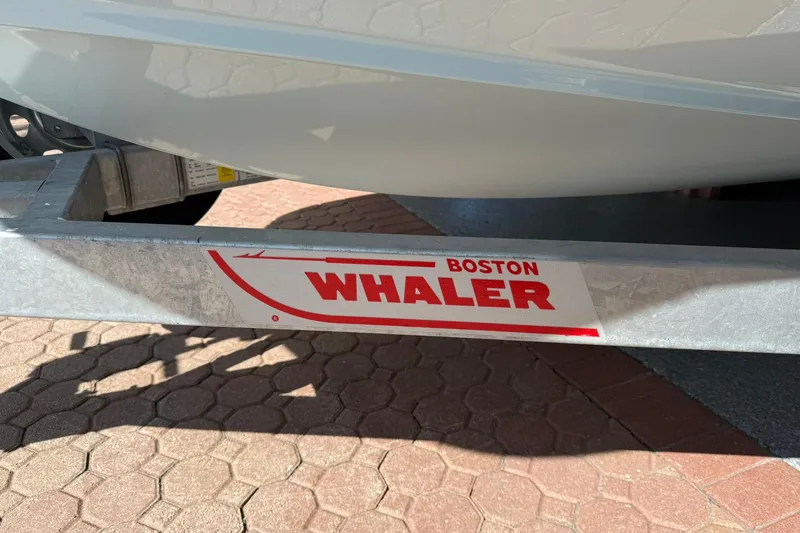 Slide: The Image of 2025 Boston Whaler 170 Montauk boat trailer with logo, parked on brick pavement. - 64