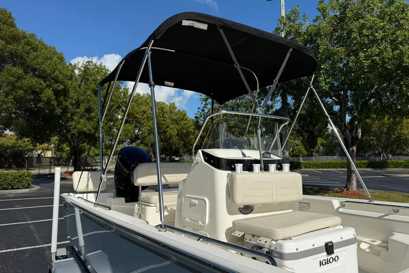 Slide: The Image of 2025 Boston Whaler 170 Montauk boat with canopy, parked outdoors under clear sky. - 8