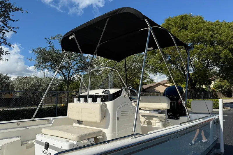 Slide: The Image of 2025 Boston Whaler 170 Montauk boat with canopy, parked outdoors under a clear blue sky. - 9