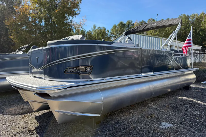The Image of 2026 Tahoe Pontoon LTZ Quad Lounger Shift, sleek design, parked outdoors, American flag displayed. - 0