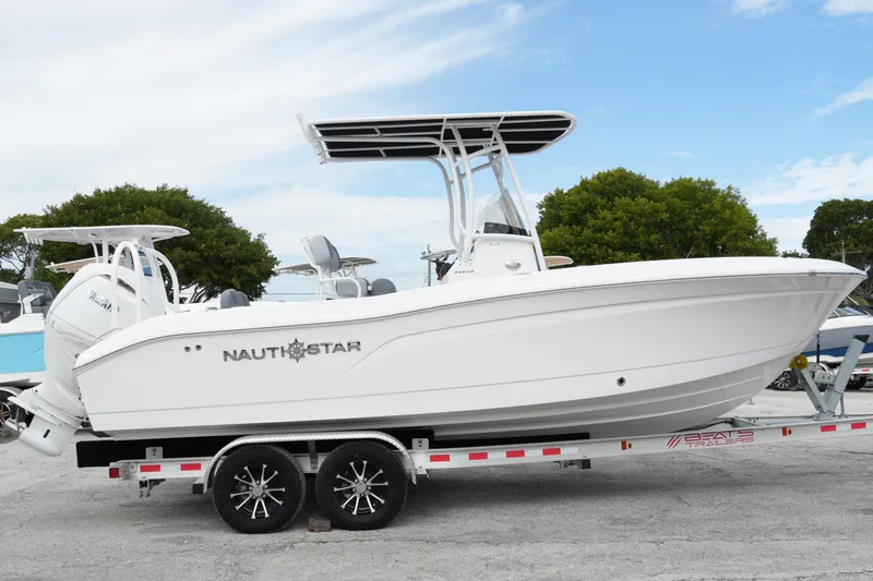Slide: The Image of 2025 NauticStar 222 Offshore boat on trailer, side view, clear sky background. - 4