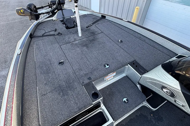 Slide: The Image of 2024 Triton 18 TrX boat deck with carpeted surface and fishing equipment. - 4