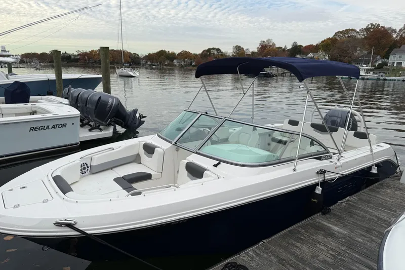 The Image of 2025 Robalo R207 Dual Console boat docked on a calm lake with scenic background. - 0