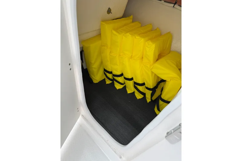 Slide: The Image of Yellow life jackets stored in a compartment of a 2025 Robalo R207 Dual Console boat. - 12