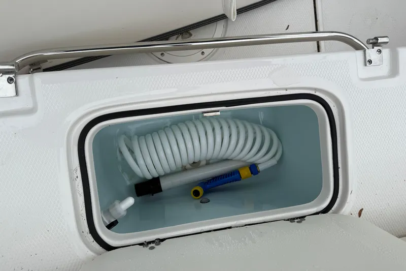 Slide: The Image of Storage compartment with coiled hose on 2025 Robalo R207 Dual Console boat. - 14