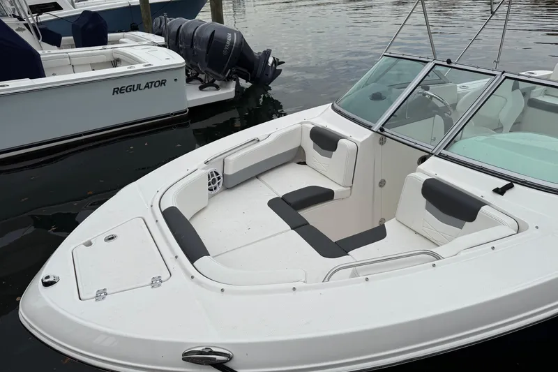 Slide: The Image of 2025 Robalo R207 Dual Console boat with spacious seating, docked beside water. - 2