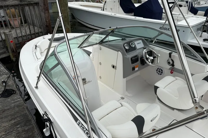 Slide: The Image of 2025 Robalo R207 Dual Console boat interior with steering wheel and seating at dock. - 5