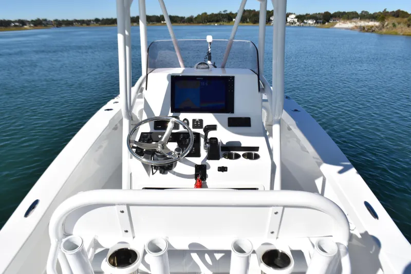 Slide: The Image of 2020 BlackJack 256 Coastal boat dashboard with steering wheel and navigation system on calm water. - 20