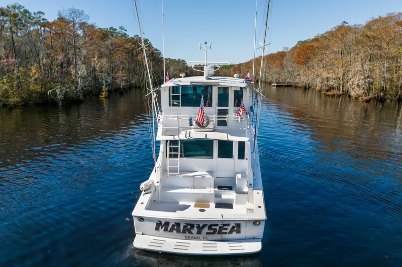 Slide: The Image of 1999 Viking 58 Convertible yacht cruising on a scenic river with autumn foliage. - 2