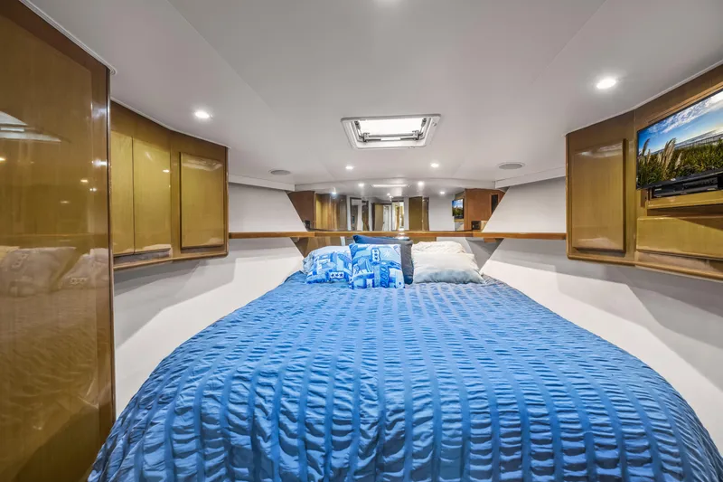 Slide: The Image of Luxurious bedroom interior of 1999 Viking 58 Convertible yacht with blue bedding and wooden cabinets. - 28