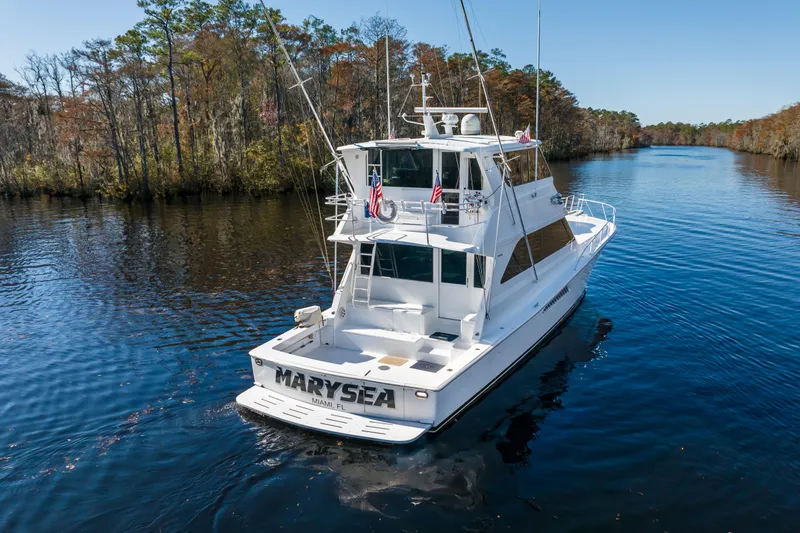 Slide: The Image of 1999 Viking 58 Convertible yacht cruising on a serene river, surrounded by lush trees. - 3
