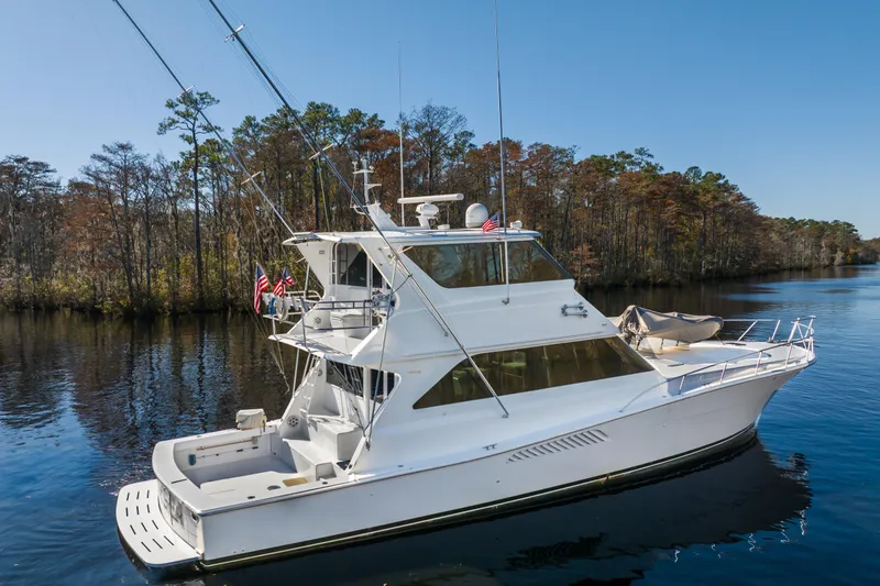 Slide: The Image of 1999 Viking 58 Convertible yacht cruising on a serene river with forested banks. - 8