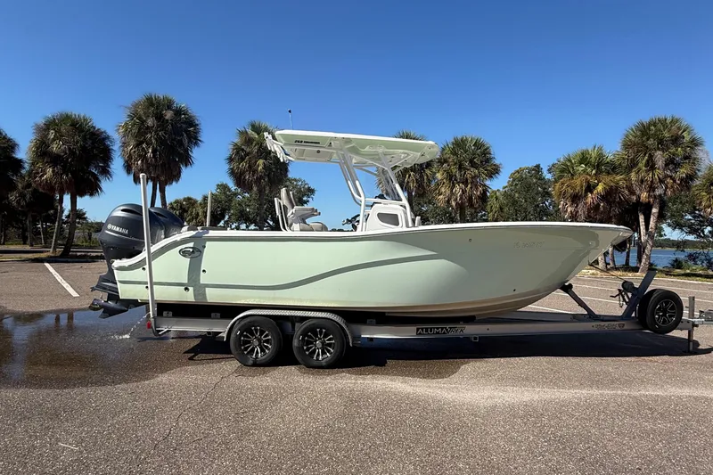 Slide: The Image of 2021 Sea Fox 268 Commander boat on trailer, parked near palm trees under clear blue sky. - 26