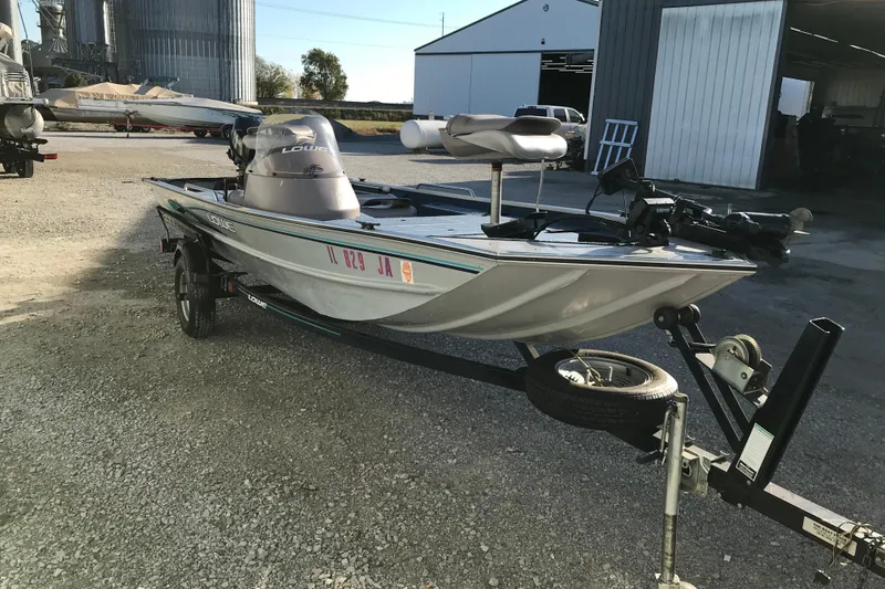 Slide: The Image of 1997 Lowe Bass Striker 170 boat on trailer, parked outdoors near industrial buildings. - 4