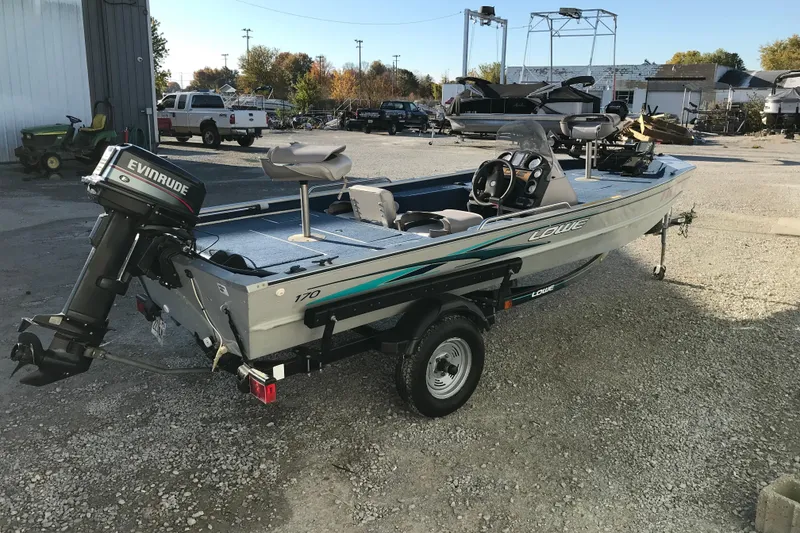 Slide: The Image of 1997 Lowe Bass Striker 170 boat with Evinrude motor on trailer, parked outdoors. - 5