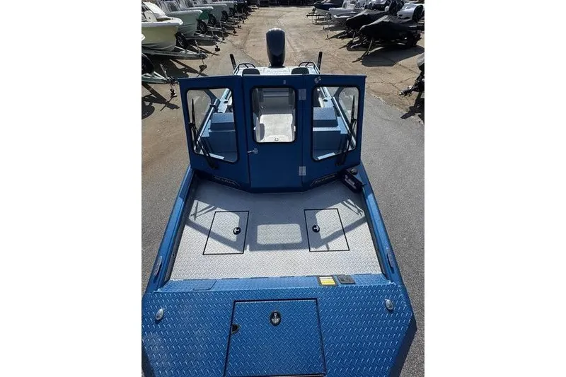 Slide: The Image of 2026 SeaArk Dynasty 2.0 boat, blue exterior, spacious deck, parked outdoors. - 15