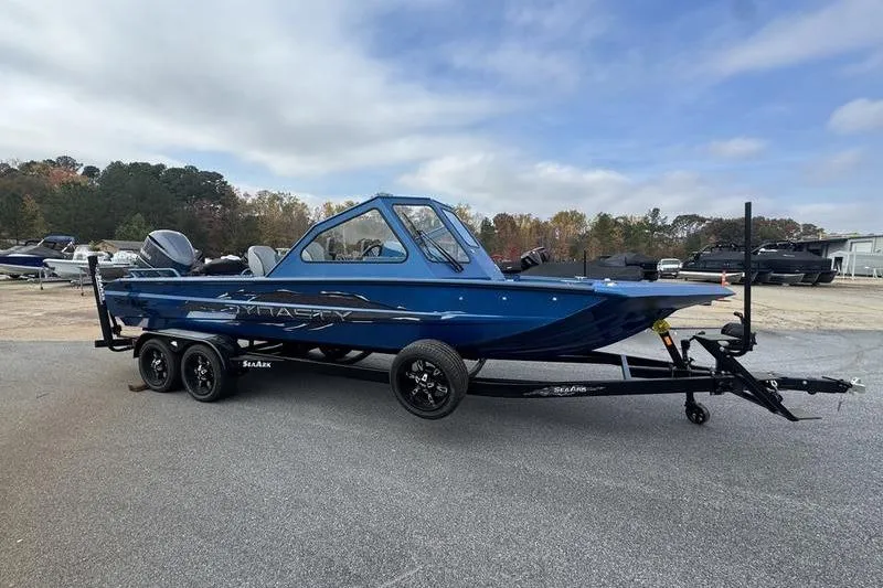 Slide: The Image of 2026 SeaArk Dynasty 2.0 boat in blue on a trailer, parked outdoors. - 17