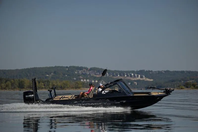 Slide: The Image of 2026 SeaArk Dynasty 2.0 boat cruising on a calm lake with scenic background. - 36