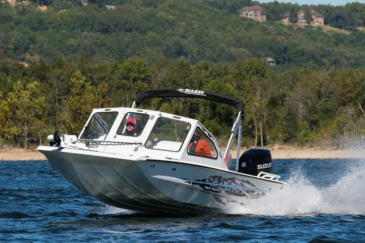 Slide: The Image of 2026 SeaArk Dynasty 2.0 boat cruising on a lake with scenic forest backdrop. - 37