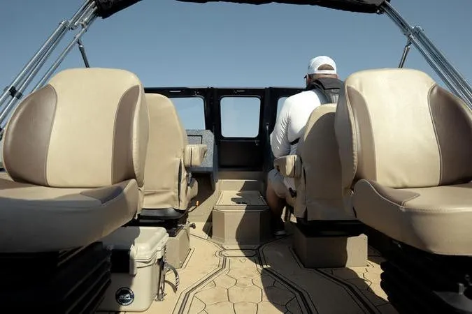 Slide: The Image of Interior view of 2026 SeaArk Dynasty 2.0 boat with beige seating and a person at the helm. - 38