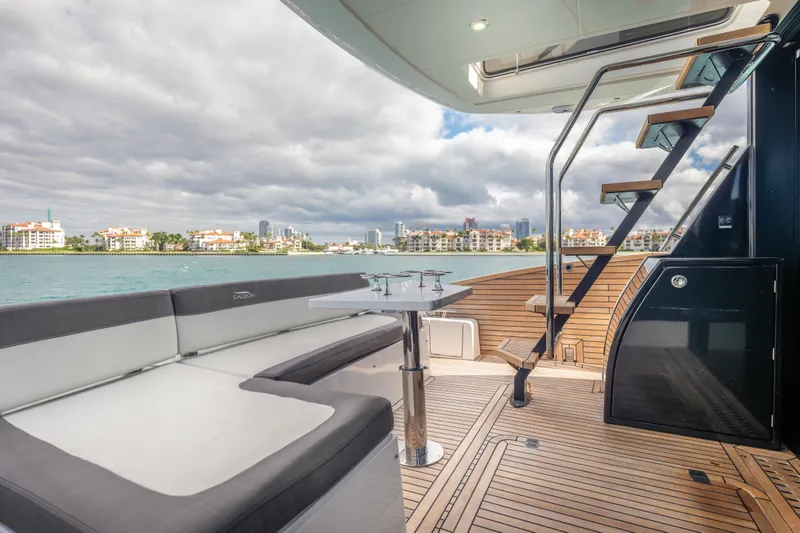 Slide: The Image of Luxury Galeon 500 Fly yacht deck with seating, table, and stairs, overlooking waterfront skyline. - 13