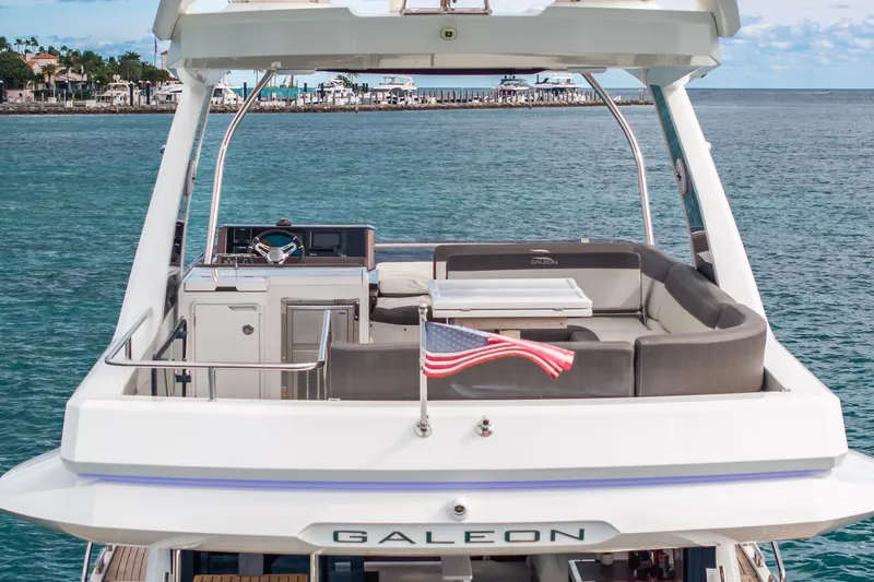 Slide: The Image of 2020 Galeon 500 Fly yacht with American flag, cruising on serene waters. - 6