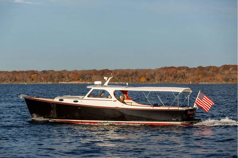 Slide: The Image of 2001 Hinckley Ya Picn boat with blue seating and American flag on water. - 10