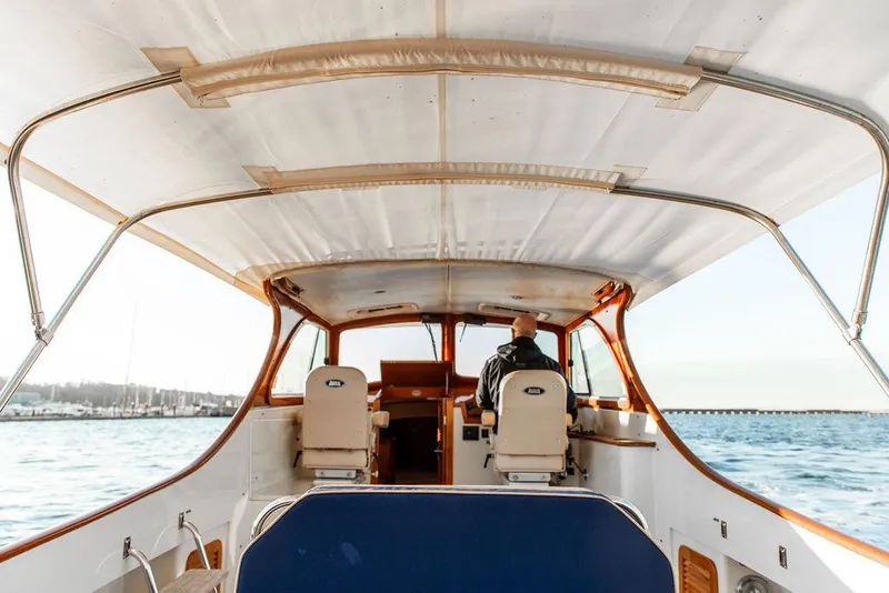 Slide: The Image of 2000 Hinckley Picnic Boat Classic cruising on a scenic lake with autumn foliage. - 2