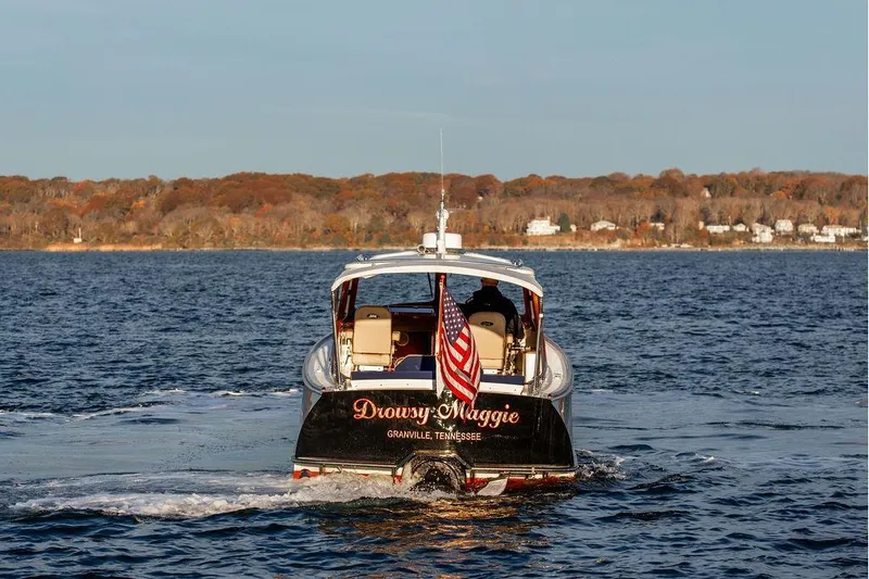 Slide: The Image of 2000 Hinckley Picnic Boat Classic cruising on a scenic lake with autumn foliage. - 6