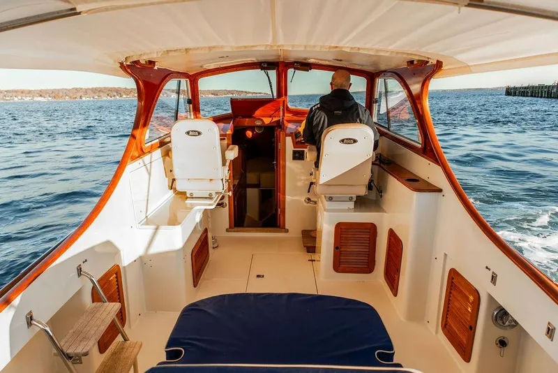 Slide: The Image of 2001 Hinckley Ya Picn boat interior with blue seating, navigating on calm waters. - 13