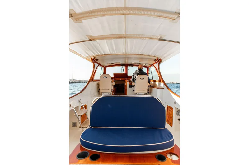 Slide: The Image of 2001 Hinckley Ya Picn boat interior with blue seating and American flag on open water. - 15