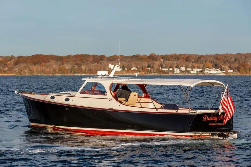 Slide: The Image of 2000 Hinckley Picnic Boat Classic cruising on a scenic lake with autumn foliage. - 5