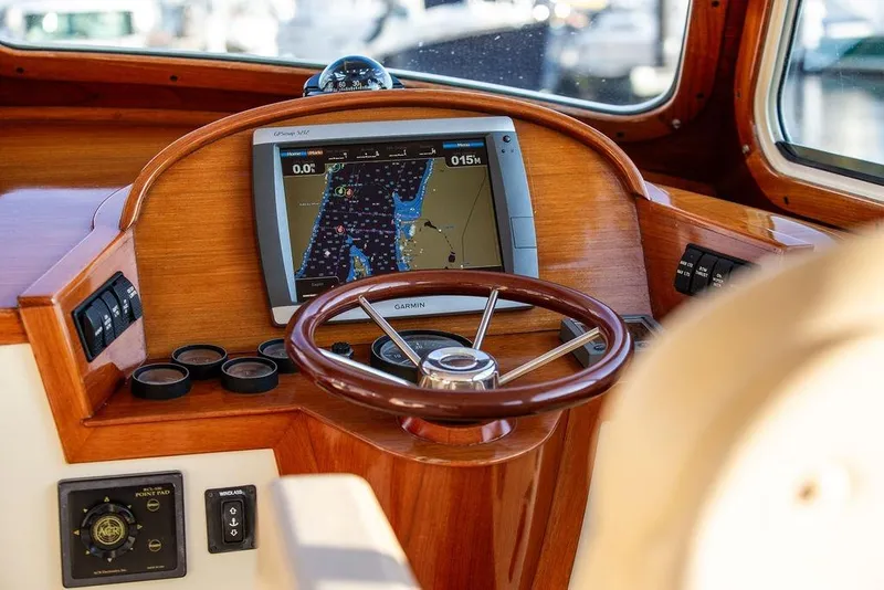 Slide: The Image of 2000 Hinckley Picnic Boat Classic cruising on a serene lake with autumn foliage backdrop. - 7