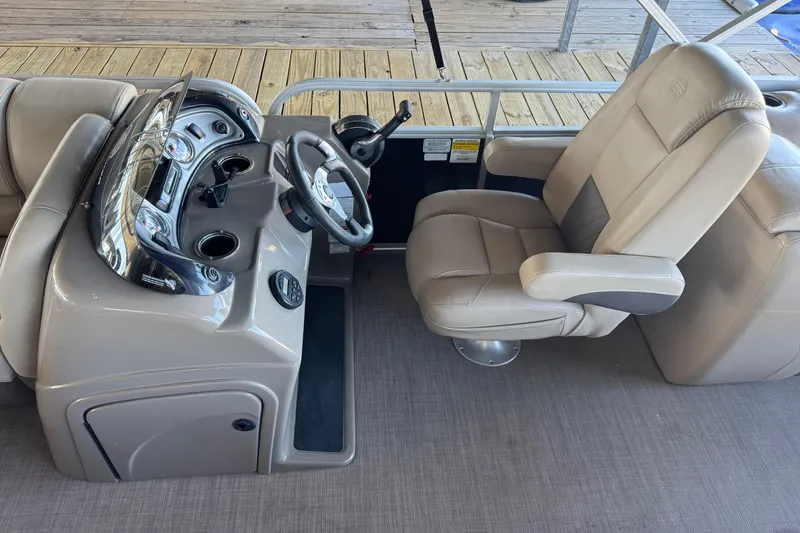 Slide: The Image of 2020 Sun Tracker Party Barge 22 DLX interior seating with cup holder, dockside view. - 12