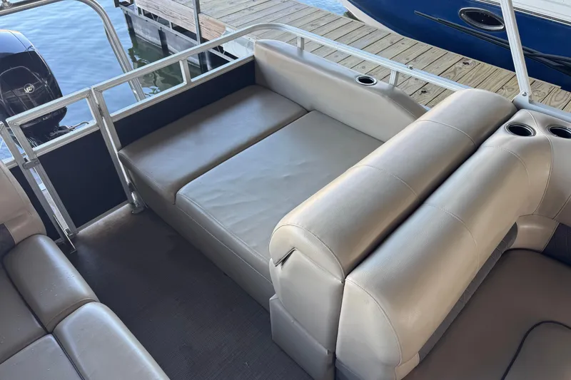 Slide: The Image of 2020 Sun Tracker Party Barge 22 DLX seating with storage compartment open on a dock. - 14
