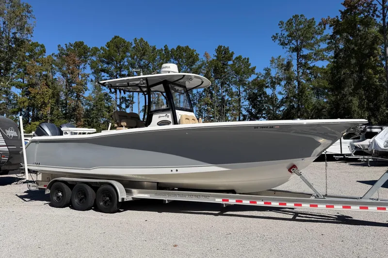 Slide: The Image of 2018 Sea Hunt Gamefish 30 Coffin Box boat on trailer, surrounded by trees. - 1