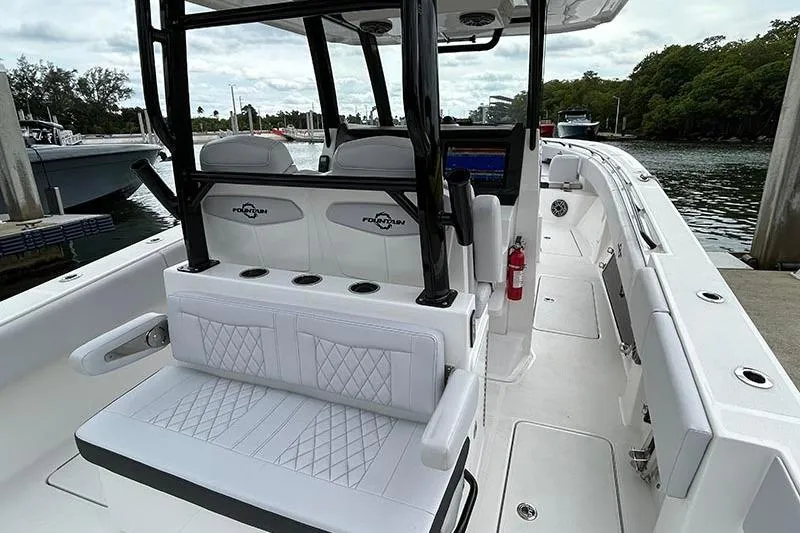 Slide: The Image of 2025 Fountain 38 Center Console boat interior with white seating and black accents at a marina. - 13