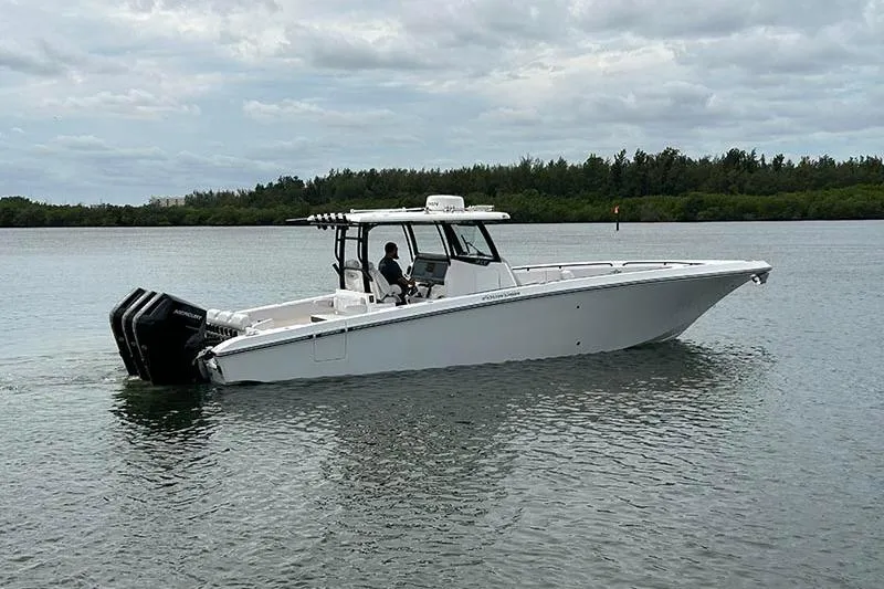 Slide: The Image of 2025 Fountain 38 Center Console boat on calm water, featuring triple outboard engines. - 2