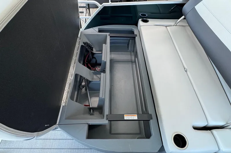 Slide: The Image of Open storage compartment in 2026 Starcraft EX 20 Q DH boat, featuring seating and cup holders. - 11