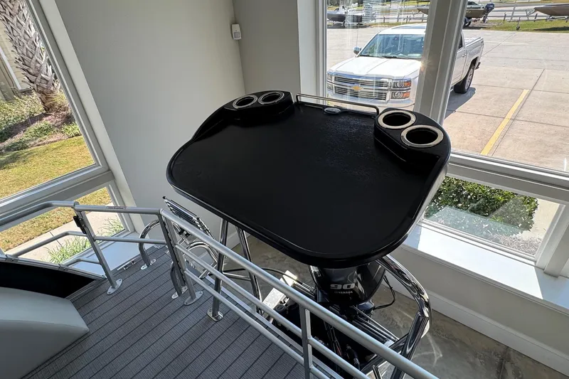 Slide: The Image of 2026 Starcraft EX 20 Q DH boat helm with cup holders, viewed indoors near large windows. - 13