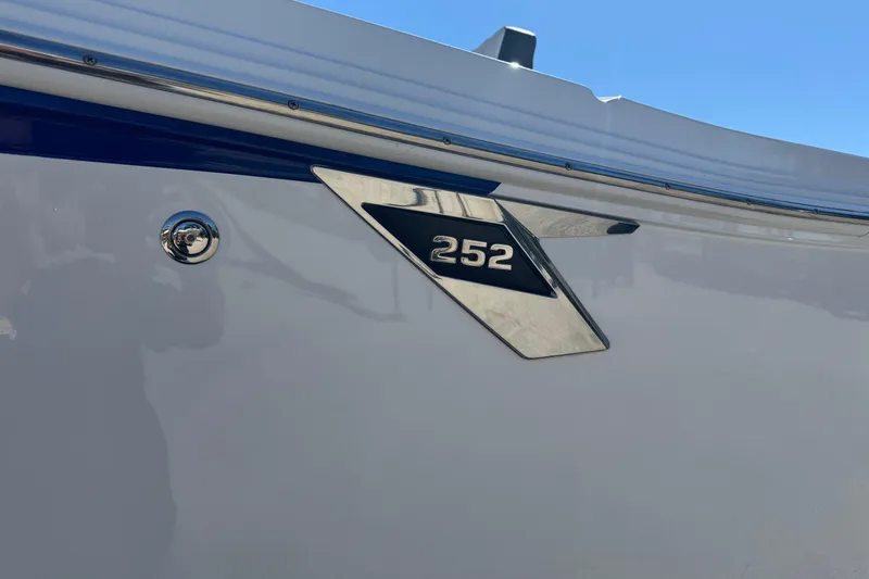 Slide: The Image of 2021 Blackfin 252 CC boat emblem on sleek white hull under clear blue sky. - 3
