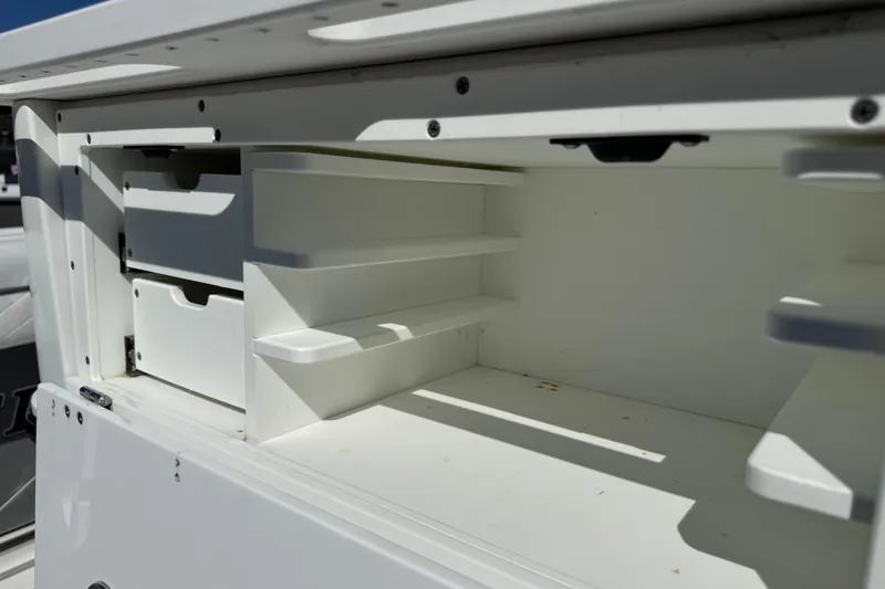 Slide: The Image of Open storage compartment on a 2021 Blackfin 252 CC boat, featuring shelves and drawers. - 9